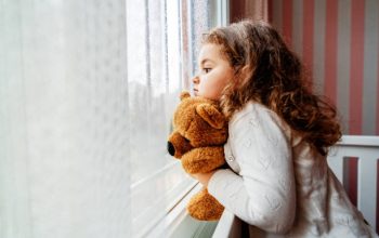 Little cute girl is watching from window to the rain with sadness get bored. . High quality photo